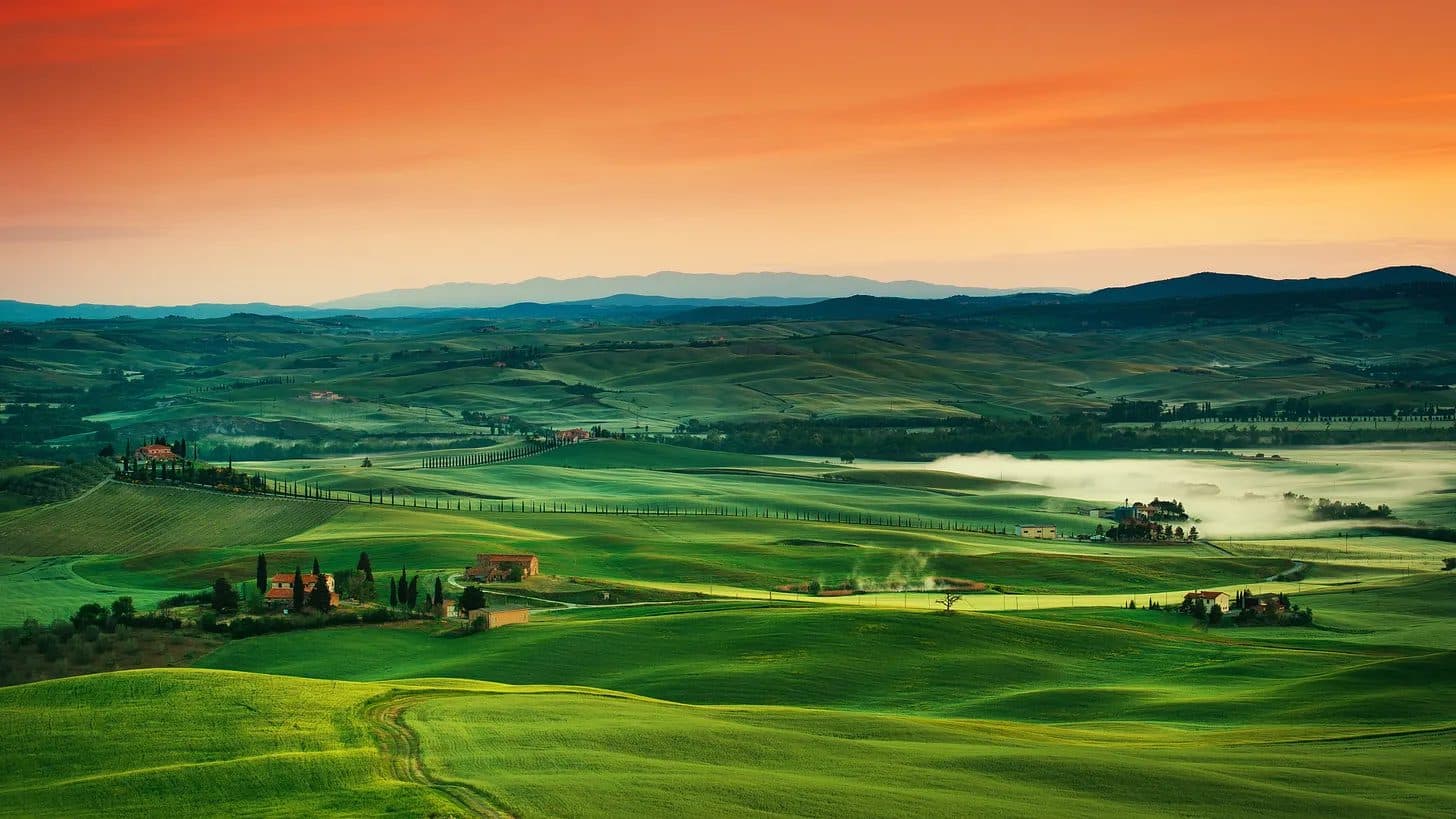 Rolling hills and farmhouses in the Tuscan countryside at sunrise